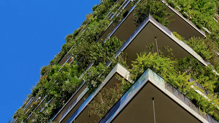 Terraços de um edifício tomados por vegetação densa contra o céu azul