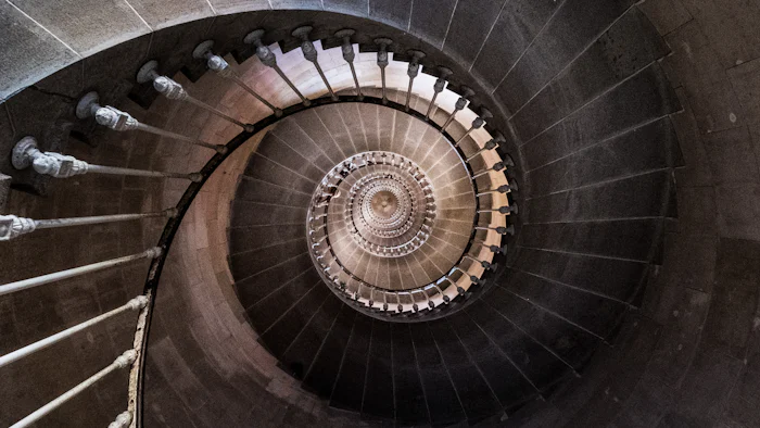 Escada em espiral fotografada de cima, com os degraus girando até o centro